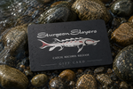 Sturgeon Slayers gift card on wet rocks with water droplets.